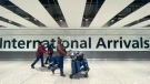 Passengers walk through International Arrivals, at London's Heathrow Airport, Friday, Nov. 26, 2021. (AP Photo/Alberto Pezzali)