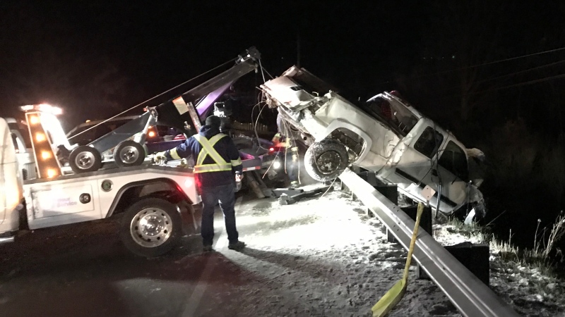Crews extricate a damaged truck from an embankment next to Highway 38 in Kingston, Ont. The driver of the truck has been charged with impaired driving. (Kingston Police)