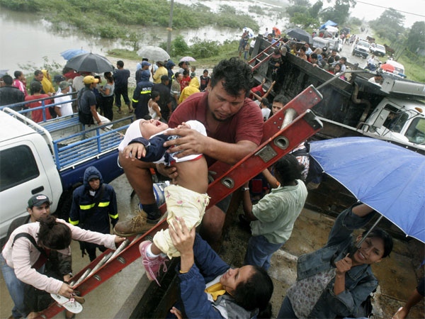 A man hands a baby to her mother during an evacuation operation after a flooding caused by Hurricane Felix in the outskirts of San Pedro Sula, eastern Honduras, Wednesday, Sept. 5, 2007. (AP / Esteban Felix) 