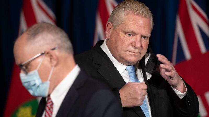 Ontario Premier Doug Ford (right) trades places with Kieran Moore, the Chief Medical Officer of Health as they attend a media briefing at the Ontario Legislature in Toronto, Friday, Dec. 17, 2021. Further restrictions were announced to combat the increasing spear of the Omicron variant of COVID-19. HE CANADIAN PRESS/Chris Young