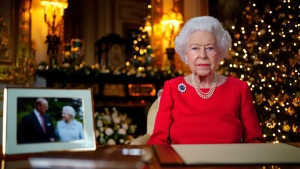 In this undated photo issued on Thursday Dec. 23, 2021, Queen Elizabeth II records her annual Christmas broadcast in Windsor Castle, Windsor, England. The photograph at left shows The Queen and Prince Philip taken in 2007 at Broadlands to mark their Diamond wedding anniversary. (Victoria Jones/Pool via AP) 