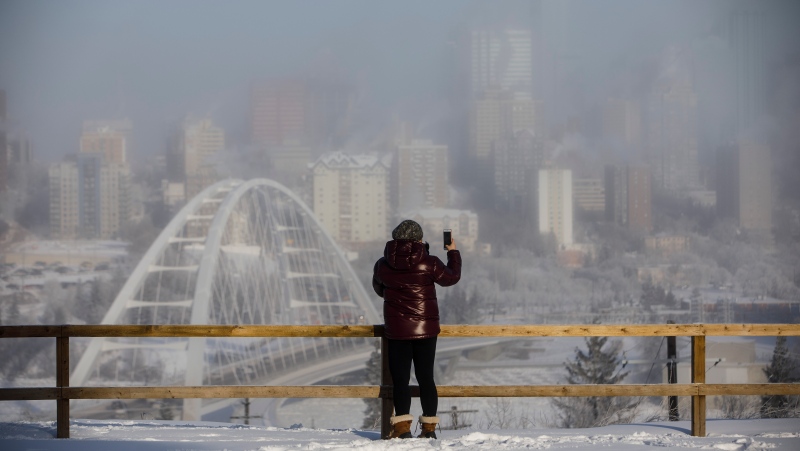 A person stops to take a picture of the city surrounded by fog, as it hits -36 C in Edmonton on Wednesday, January 15, 2020. THE CANADIAN PRESS/Jason Franson 