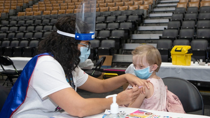 Five-year-old Hannah Schmid receives her COVID-19 vaccine shot from Dr. Chetana Kulkarni from Sick Kids Hospital at a children's vaccine clinic held at the Scotiabank Arena, in Toronto, on Sunday, Dec. 12, 2021. (THE CANADIAN PRESS/Chris Young)