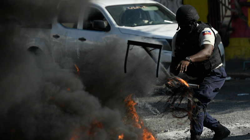 Police try to clear a burning roadblock set by anti-government protesters in order for vehicles to pass in Port-au-Prince, Haiti, Thursday, Oct. 28, 2021. (AP Photo/Matias Delacroix) 