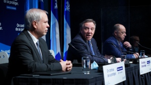 Dr. Luc Boileau, left, interim Quebec Director of Public Health, is presented by Premier Francois Legault with Health Minister Christian Dube during a news conference in Montreal, Tuesday, Jan. 11, 2022. THE CANADIAN PRESS/Paul Chiasson 