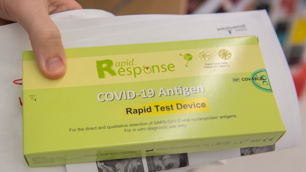 A man displays his COVID-19 rapid test kit after receiving it at a pharmacy in Montreal, Monday, December 20, 2021, as the COVID-19 pandemic continues in Canada and around the world. (THE CANADIAN PRESS / Graham Hughes)
