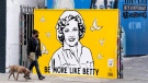 A man walks a dog past a new mural of the late actress Betty White by artist Corie Mattie, on Jan. 13, 2022. (Chris Pizzello / AP)