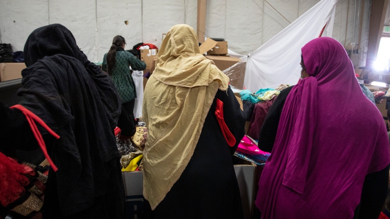 FILE - Afghan refugees look for donated clothing and shoes at the donation center at the Fort McCoy U.S. Army base on Thursday, Sept. 30, 2021, in Fort McCoy, Wis. (Barbara Davidson/Pool Photo via AP) 