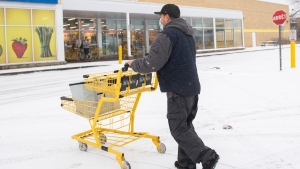 A man pushes a shopping cart towards a closed grocery store in Montreal, Sunday, Jan. 9, 2022. The Quebec government has introduced measures to help curb the spread of COVID-19, including the closure of grocery stores for three Sundays. THE CANADIAN PRESS/Graham Hughes