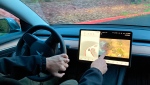 Vince Patton, a new Tesla owner, demonstrates on Dec. 8, 2021, on a closed course in Portland, Ore., how he can play video games on the vehicle's console while driving. (AP Photo/Gillian Flaccus, File) 