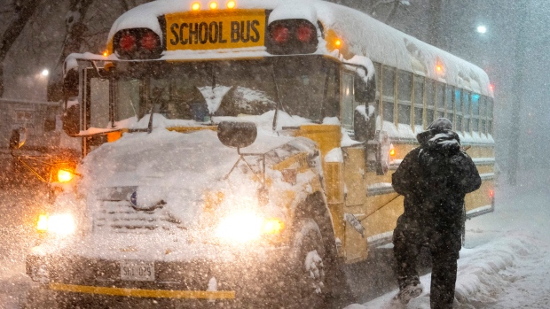A school bus driver tries to clear snow as a winter storm causes the closure of schools in Toronto on Monday January 17, 2022. THE CANADIAN PRESS/Frank Gunn 

