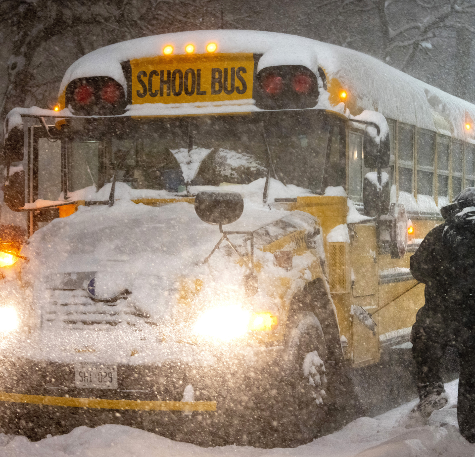 A school bus driver tries to clear snow 