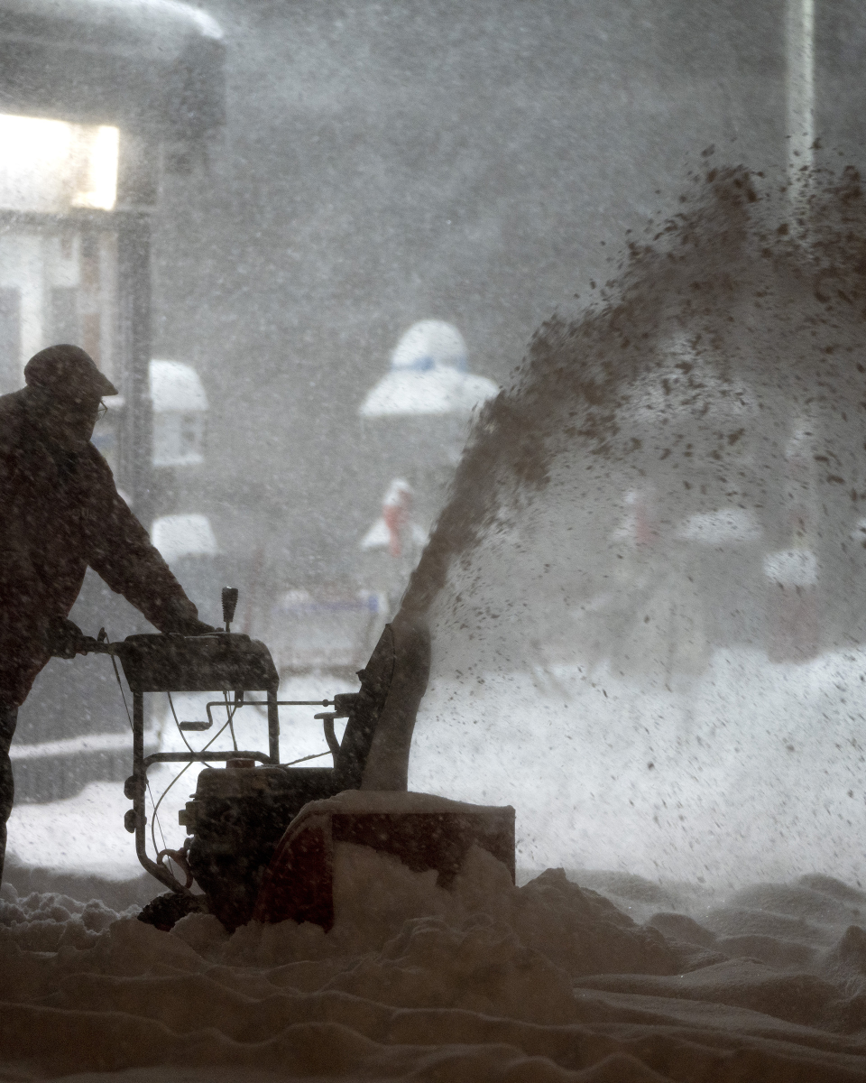A man clears snow at a gas station