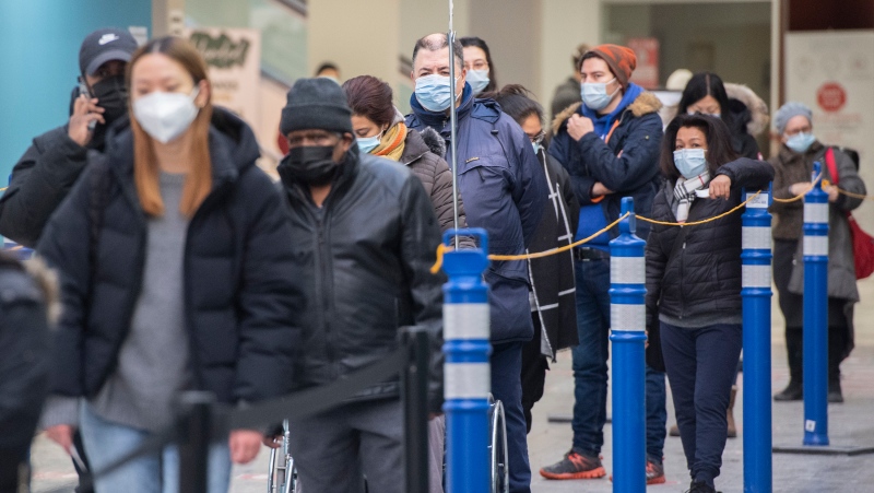 People wait in line at a COVID-19 vaccination site in Montreal, Sunday, January 16, 2022, as the COVID-19 pandemic continues in Canada. THE CANADIAN PRESS/Graham Hughes 