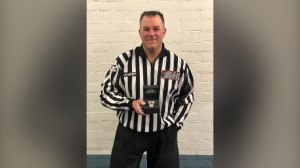 Linesman Kevin Hastings stands poses with the commemorative watch given to him to mark his 1,000th game. (Kitchener Rangers/Twitter)