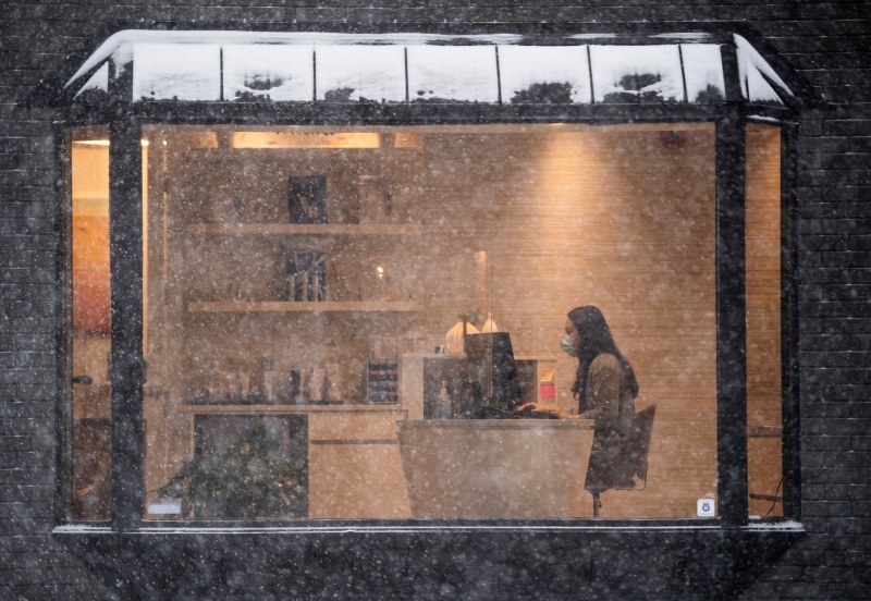 A person works inside a business as snow falls outside in Ottawa, on Monday, Jan. 17, 2022. A blizzard warning is in effect for the region with Environment Canada predicting between 25 to 40 cm of snow. (Justin Tang/THE CANADIAN PRESS)