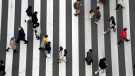 People wearing protective masks to help curb the spread of the coronavirus walk along a pedestrian crossing Monday, Jan. 17, 2022, in Tokyo. (AP Photo/Eugene Hoshiko)