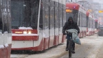 A cyclict makes his way past dozens of stranded streetcars during a severe winter storm in Toronto on Monday January 17, 2022. THE CANADIAN PRESS/Frank Gunn 
