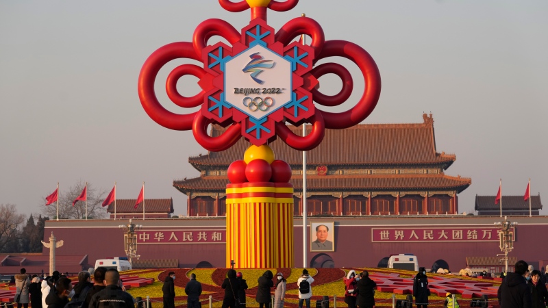 Residents look at a Beijing Winter Olympics decoration on Tiananmen Square in Beijing, China, Tuesday, Jan. 18, 2022. (AP Photo/Ng Han Guan) 