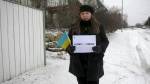 Inna Platonova holds a Ukrainian flag and a sheet of paper that says 'stand with Ukraine' in Calgary. Members of the city's Ukrainian community are calling for allies to do more to support the European nation. 