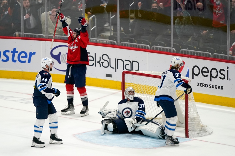 Washington Capitals right wing Tom Wilson celebrates after scoring a game-winning goal in front of Winnipeg Jets defenseman Josh Morrissey (44), goaltender Connor Hellebuyck (37) and left wing Kyle Connor (81) in an overtime period of an NHL hockey game, Tuesday, Jan. 18, 2022, in Washington. Washington won 4-3 in overtime. (AP Photo/Patrick Semansky) 