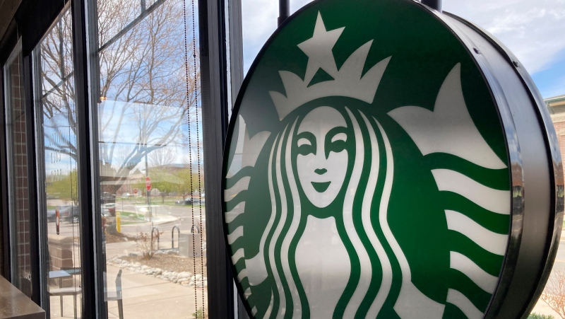 A sign bearing the corporate logo hangs in the window of a Starbucks open only to take-away customers in this photograph taken Monday, April 26, 2021, in southeast Denver. (AP Photo/David Zalubowski) 