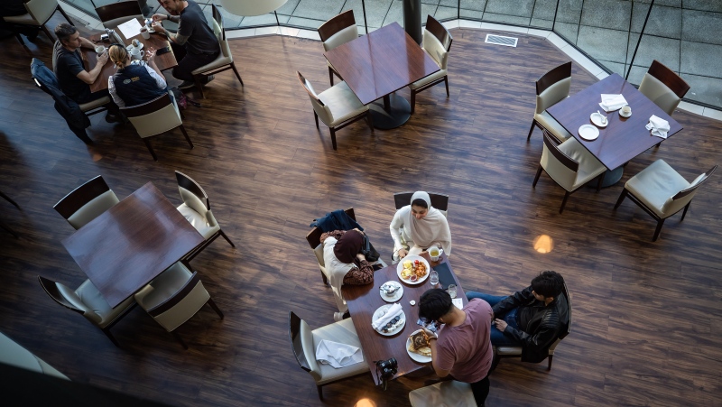 A server brings food to a table as people dine at a restaurant in Vancouver, on Tuesday, September 21, 2021. British Columbia's COVID-19 vaccine card system went into effect last week. Anyone who wants access to a range of non-essential indoor services, including restaurants, must show proof of at least one dose of vaccine, with a second shot required by Oct. 24. THE CANADIAN PRESS/Darryl Dyck 