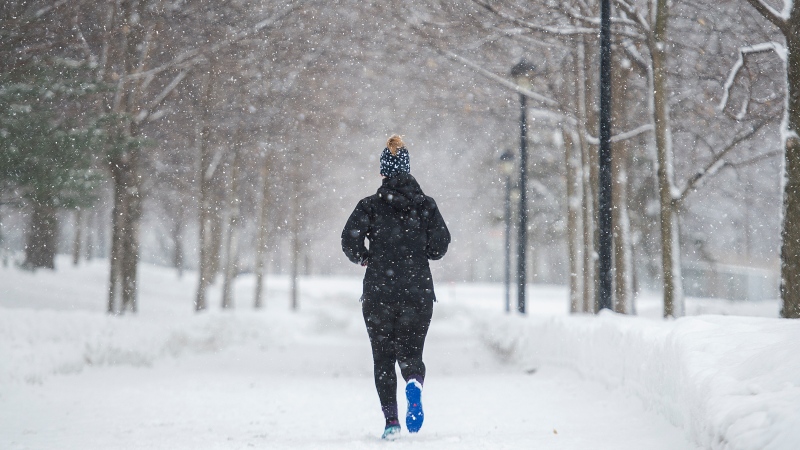 A person jogs in a park as snow falls in Montreal in this Saturday, February 27, 2021 file photo. (THE CANADIAN PRESS/Graham Hughes)