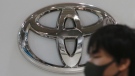 In this Nov. 2, 2020, file photo, a visitor wearing a face mask to help curb the spread of the coronavirus walks by the logo of Toyota Motor Corp. at its showroom in Tokyo. (AP Photo/Koji Sasahara, File)