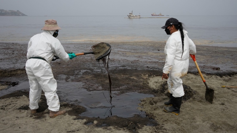 Workers, dressed in protective suits, continue to clean the oil contaminated Conchitas Beach, in Ancon, Peru, Jan. 20, 2022. (AP Photo/Martin Mejia)