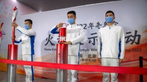 Officials place the Olympic flame and an Olympic torch on pedestals during an event at the Beijing University of Posts and Communications in Beijing on Dec. 9, 2021. (AP Photo/Mark Schiefelbein)