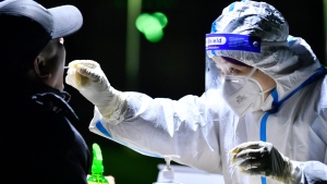 In this photo released by China's Xinhua News Agency, a worker wearing a protective suit takes a swab for a coronavirus test as part of a round of citywide COVID-19 testing in northern China's Tianjin Municipality, Thursday, Jan. 20, 2022. (Sun Fanyue/Xinhua via AP) 