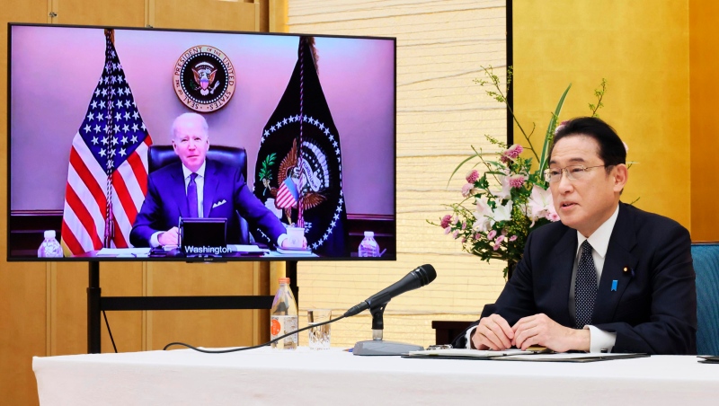 Japanese Prime Minister Fumio Kishida, right, sitting in a room of the prime minister's official residence in Tokyo, Friday, Jan. 21, 2022, talks in a virtual meeting with U.S. President Joe Biden, shown in the monitor. (Cabinet Secretariat/Kyodo News via AP) 