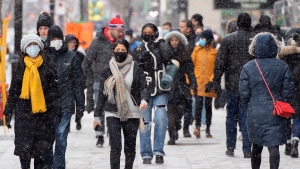 People wear face masks as they walk along Ste-Catherine Street in Montreal, Saturday, Dec. 4, 2021. THE CANADIAN PRESS/Graham Hughes 
