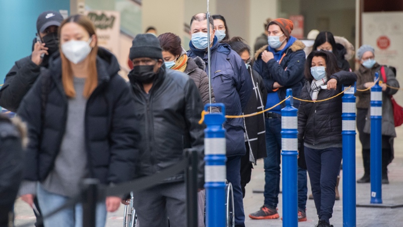 People wait in line at a COVID-19 vaccination site in Montreal, Sunday, January 16, 2022, as the COVID-19 pandemic continues in Canada. (THE CANADIAN PRESS / Graham Hughes)