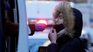 A woman wearing a winter coat gets tested for COVID-19 at a mobile testing site in New York, Tuesday, Jan. 11, 2022.  (AP Photo/Seth Wenig) 
