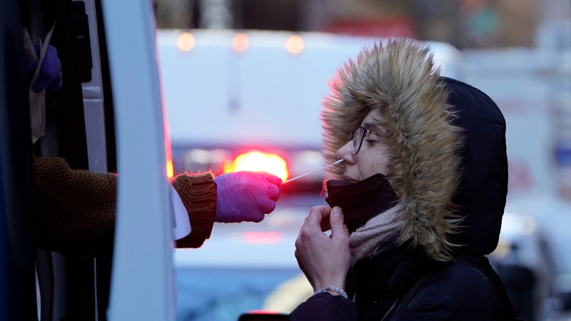 A woman wearing a winter coat gets tested for COVID-19 at a mobile testing site in New York, Tuesday, Jan. 11, 2022.  (AP Photo/Seth Wenig) 