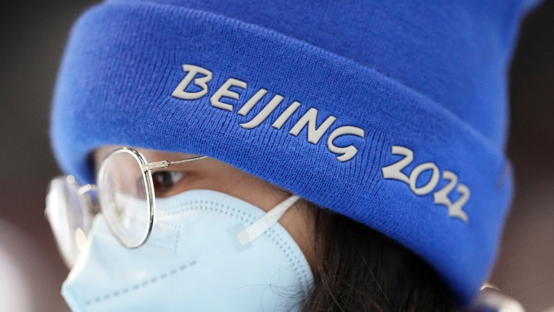 A woman wears a Beijing 2022 hat while walking inside the main media center at the 2022 Winter Olympics, Saturday, Jan. 22, 2022, in Beijing. (AP Photo/David J. Phillip) 
