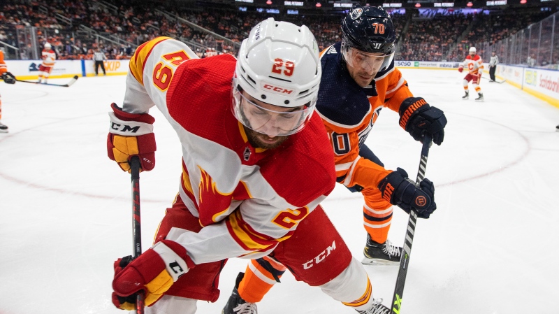 Calgary Flames' Dillon Dube (29) and Edmonton Oilers' Colton Sceviour (70) battle for the puck during first period NHL action in Edmonton on Saturday, January 22, 2022 (The Canadian Press/Jason Franson).