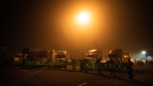 Truckers and supporters raise their fists and hold a banner before a cross-country convoy destined for Ottawa to protest a federal vaccine mandate for truckers departed in Delta, B.C. on Sunday, January 23, 2022. THE CANADIAN PRESS/Darryl Dyck