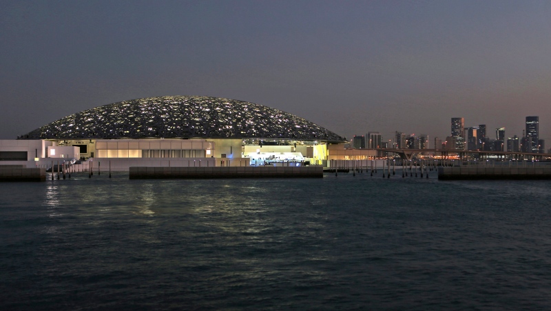 In this Monday, Nov. 6, 2017, photo, the night view of Louvre Abhu Dhabi is seen in front of the city skyline in Abu Dhabi, United Arab Emirates. (AP Photo/Kamran Jebreili) 