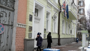 A woman walks past a security guard at the British Embassy in Kyiv, Ukraine, Monday, Jan. 24, 2022. Britain on Monday also announced it is withdrawing some diplomats and dependants from its embassy in Kyiv. The Foreign Office said the move was "in response to the growing threat from Russia." (AP Photo/Efrem Lukatsky) 