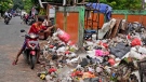 A man adds a bag of waste to an open garbage dump in Jakarta, Indonesia, on Jan. 25, 2022. (AP Photo/Dita Alangkara)