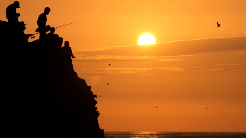 People are silhouetted while fishing during sunset at Herradura beach in Lima, Peru, on Jan. 15, 2022. (Martin Mejia / AP) 