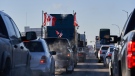 Protesters of COVID-19 restrictions, and supporters of Canadian truck drivers protesting the COVID-19 vaccine mandate cheer on a convoy of trucks on their way to Ottawa, on the Trans-Canada Highway west of Winnipeg, Manitoba, Tuesday January 25, 2022. THE CANADIAN PRESS/David Lipnowski