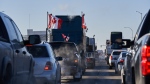 Protesters of COVID-19 restrictions, and supporters of Canadian truck drivers protesting the COVID-19 vaccine mandate cheer on a convoy of trucks on their way to Ottawa, on the Trans-Canada Highway west of Winnipeg, Manitoba, Tuesday January 25, 2022. THE CANADIAN PRESS/David Lipnowski 