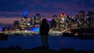 A woman is silhouetted by the lights of downtown Vancouver as she stands in a park in North Vancouver, B.C., Wednesday, Jan. 12, 2022. (Jonathan Hayward / THE CANADIAN PRESS)