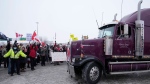 A police officer helps a truck pull out of a parking lot as people carrying Canadian flags look on in Toronto on Thursday Jan. 27, 2022. THE CANADIAN PRESS/Frank Gunn 
