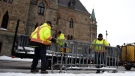 Public Works staff prepare fencing in front of Parliament Hill’s West Block in Ottawa, on Thursday, Jan. 27, 2022, before a cross-country convoy protesting a federal vaccine mandate for truckers is expected on Saturday. THE CANADIAN PRESS/Justin Tang 