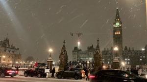 A group of people gather outside Parliament Hill on Thursday evening, one day before truckers and supporters are scheduled to arrive in Ottawa for the Freedom Convoy. (Jackie Perez/CTV News Ottawa)
